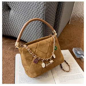 Detail of brown suede quilted handbag with golden chain charms and cylindrical handle
