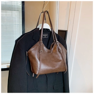Detail view of deep brown vintage tote bag hanging on a suit hanger showing its texture