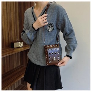 Close-up of brown vintage crossbody bag with silver skull ornament and metal eyelets