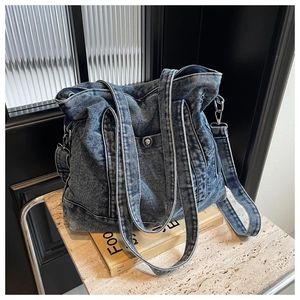 Macro detail of dark blue washed denim tote bag with silver metal buckles and texture