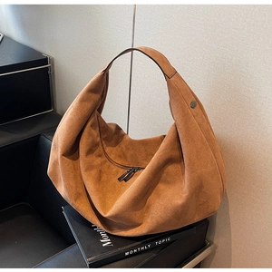 Detail of hobo shoulder bag in brown suede with metallic double zippers and round studs