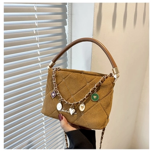 Detail of brown quilted suede handbag featuring colorful enamel heart charms and gold chain