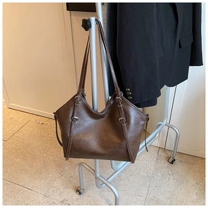 Detail view of large dark brown tote bag with premium leather texture and silver buckles