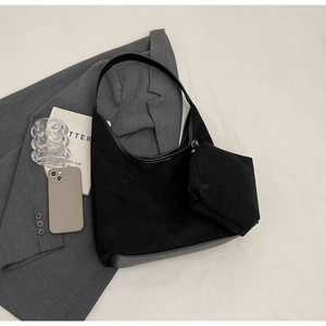Détail du sac hobo en daim noir avec mini pochette assortie et accessoires de mode