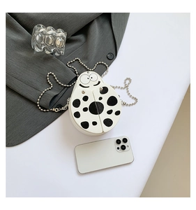 Mini ladybug pattern crossbody bag with chain strap next to a smartphone for size