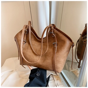 Macro shot of brown PU leather tote bag with vintage texture and silver buckle details