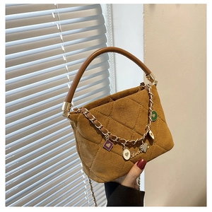 Close-up of brown quilted handbag with heart charms and metal chain detailing