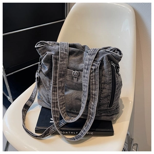 Detail of gray washed denim tote bag featuring metal zipper pocket and vintage texture