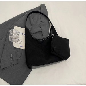 Détail du sac hobo en daim noir avec petite pochette sur un fond au style minimaliste