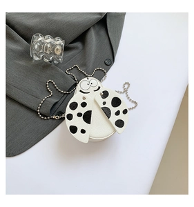 Detailed view of mini ladybug crossbody bag with silver chain strap on a textured surface
