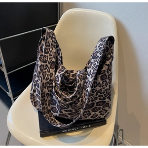 Detail of leopard print tote bag with wide shoulder strap on a white designer chair