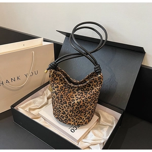 Detailed macro view of leopard print bucket bag with black rope straps and gold charm