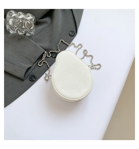 Detailed view of mini white pear-shaped bag with silver bead chain on white surface