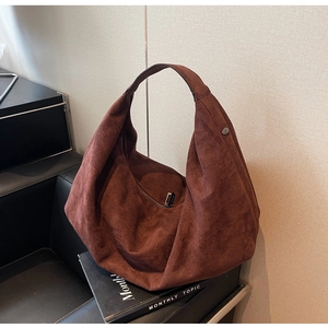 Close-up of large brown suede tote bag featuring metallic magnetic snap and wide shoulder strap