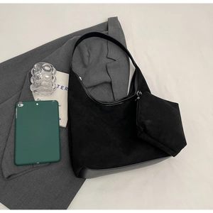 Détail d'un sac hobo en daim noir avec mini pochette assortie dans un décor lifestyle chic