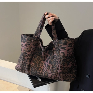 Detail of large leopard print tote bag in dark purple fabric held by model