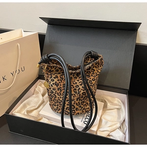 Detailed close-up of leopard print tote bag with black straps and golden charm in gift box