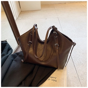 Detail of vintage textured dark brown tote bag with metal buckles and long shoulder straps