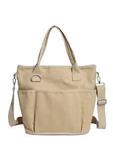 Minimalist beige canvas tote bag with three front pockets and adjustable shoulder strap