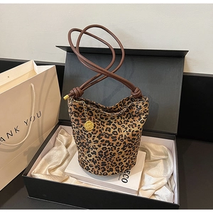 Detail of leopard print tote bag featuring thin brown handles and a gold flower charm