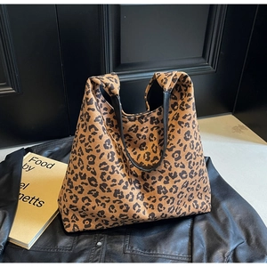 Détail du sac cabas imprimé léopard avec poignées en cuir noir et texture en daim