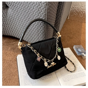 Detail of black quilted handbag with golden heart charms on an open book background