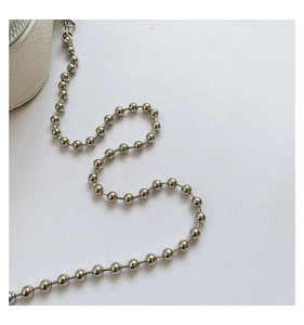 Detail of silver beaded metal chain strap on white lychee pattern leather handbag