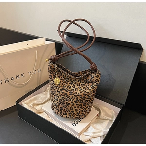 Detailed view of leopard print tote bag with golden rose charm inside a gift box