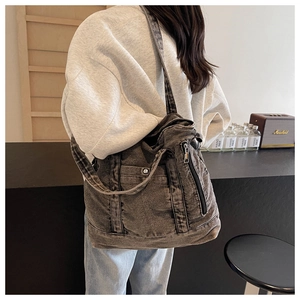 Detail view of washed grey denim tote bag with side zipper pocket and metal snap button
