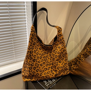 Détail du sac cabas imprimé léopard avec bandoulière en cuir noir sous un éclairage studio