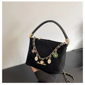 Detail of black velvet quilted handbag featuring golden heart charms and elegant top handle