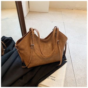 Detail view of a vintage brown tote bag with side ties and polished silver hardware