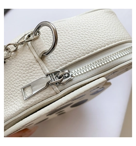 Detail shot of white lychee-patterned PU leather and silver metal zipper on kids bag