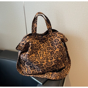 Detail of a leopard print tote bag with double handles on a black leather sofa
