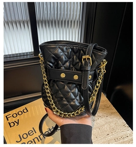 Detail of black quilted leather bucket bag with gold chain strap and stitching