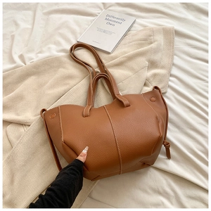 Detailed close-up of brown pebbled leather tote bag with elegant white contrast stitching