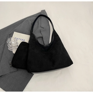 Détail d'un sac cabas noir en daim avec pochette assortie sur un fond de style épuré