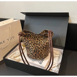 Detailed view of leopard print tote bag with thick rope handles and gold floral pendant charm