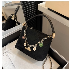 Detail view of black quilted handbag with colorful heart charms and gold chain handles