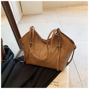 Detail view of caramel brown faux leather tote showing grain texture and silver buckles