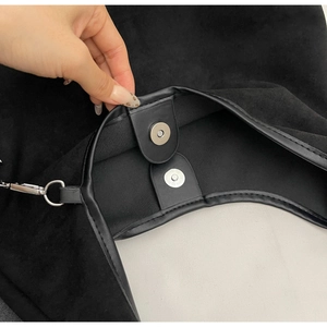 Détail du sac bandoulière en daim noir avec fermeture magnétique et bordure en cuir
