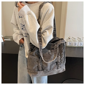 Detail view of washed denim tote bag with metal button pocket and wide shoulder strap