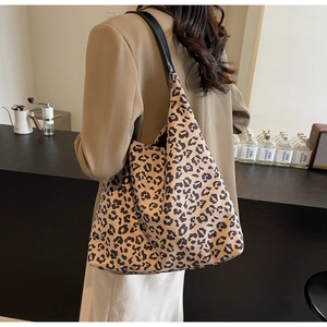 Détail d'un grand sac cabas à imprimé léopard porté à l'épaule dans un café chic