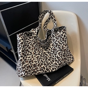 Detailed macro view of high-capacity leopard print tote bag on a stylish white chair