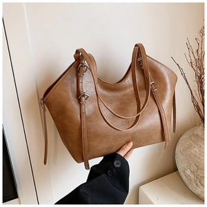 Close-up of vintage brown tote bag leather texture with silver buckles and slim straps