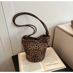 Detailed view of leopard print bucket bag with knotted brown strap and gold chain accent