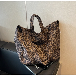 Detail of large leopard print tote bag featuring sturdy handles and adjustable shoulder strap