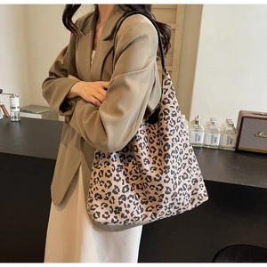 Sac fourre-tout à motif léopard avec fines anses noires porté sur une veste marron chic