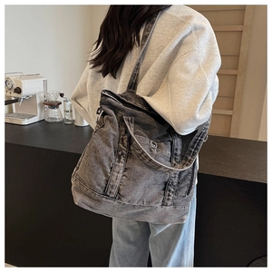 Rear view of a model wearing the vintage wash grey denim tote bag in a cozy cafe setting