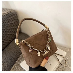 Detailed macro of brown quilted handbag with gold chains and heart shaped charms